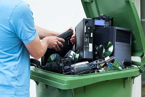 Electronics being placed in a recycling bin